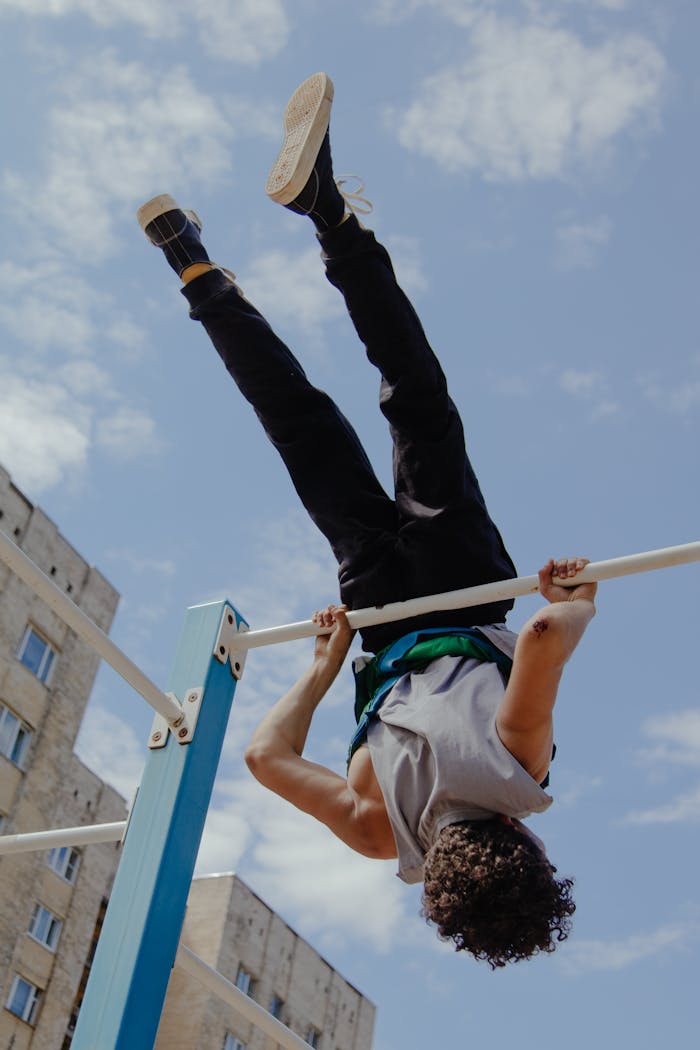 Man performing a dynamic handstand on outdoor parallel bars with city backdrop.